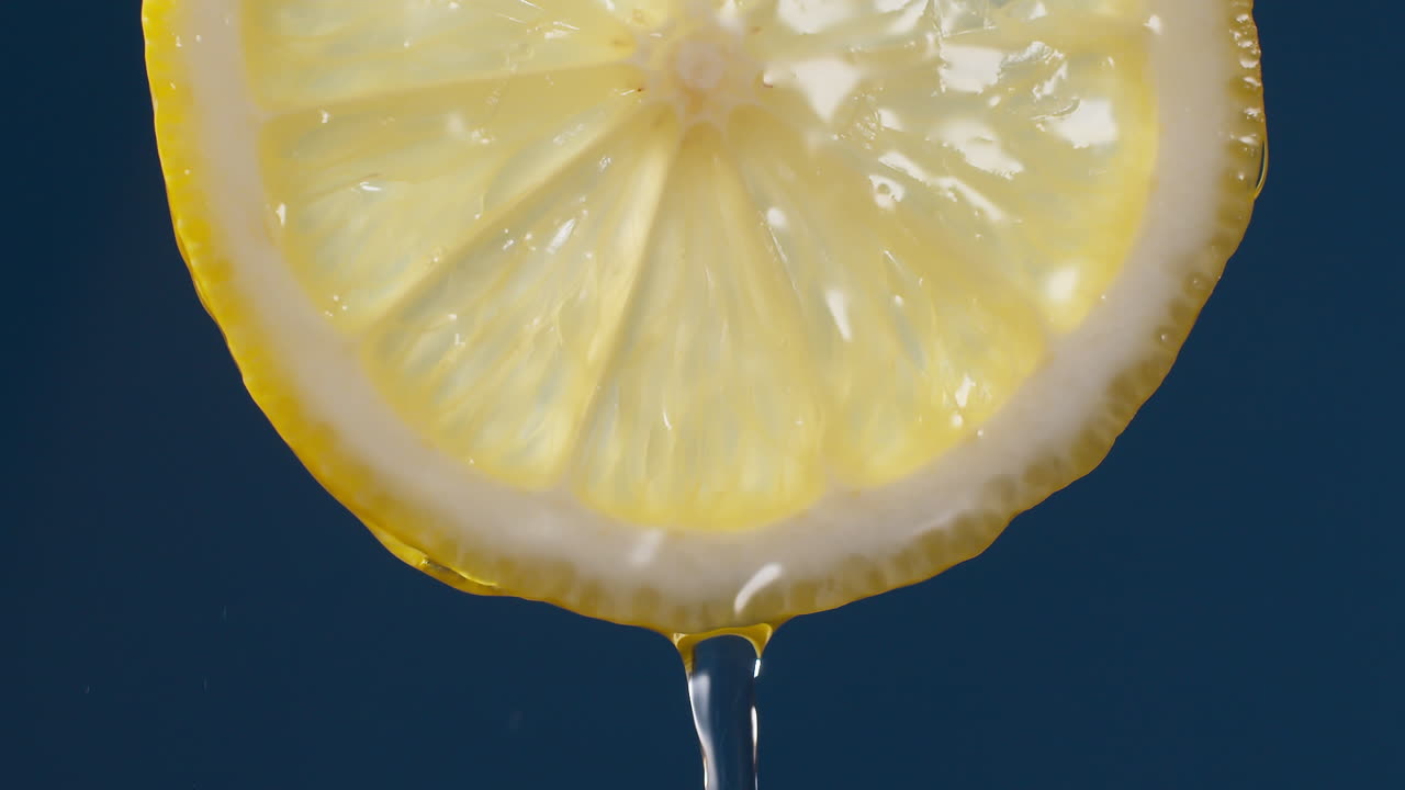 slow motion makro skud af flydende vand fra citron skive på blå-sort baggrund