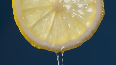 slow motion macro shot of flowing water from lemon slice on blue-black background