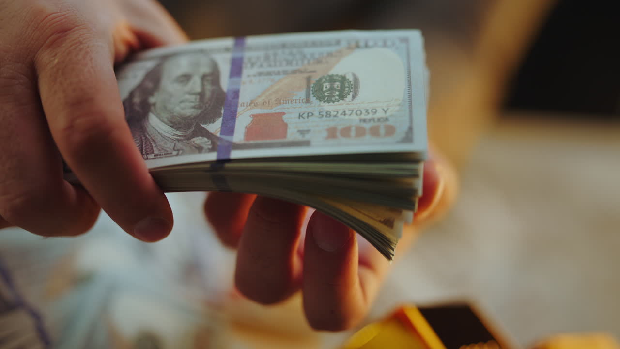 A Hand Holding a Stack of Hundred Dollar Bills