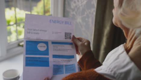 worried senior woman with uk energy bill concerned about cost of living energy crisis