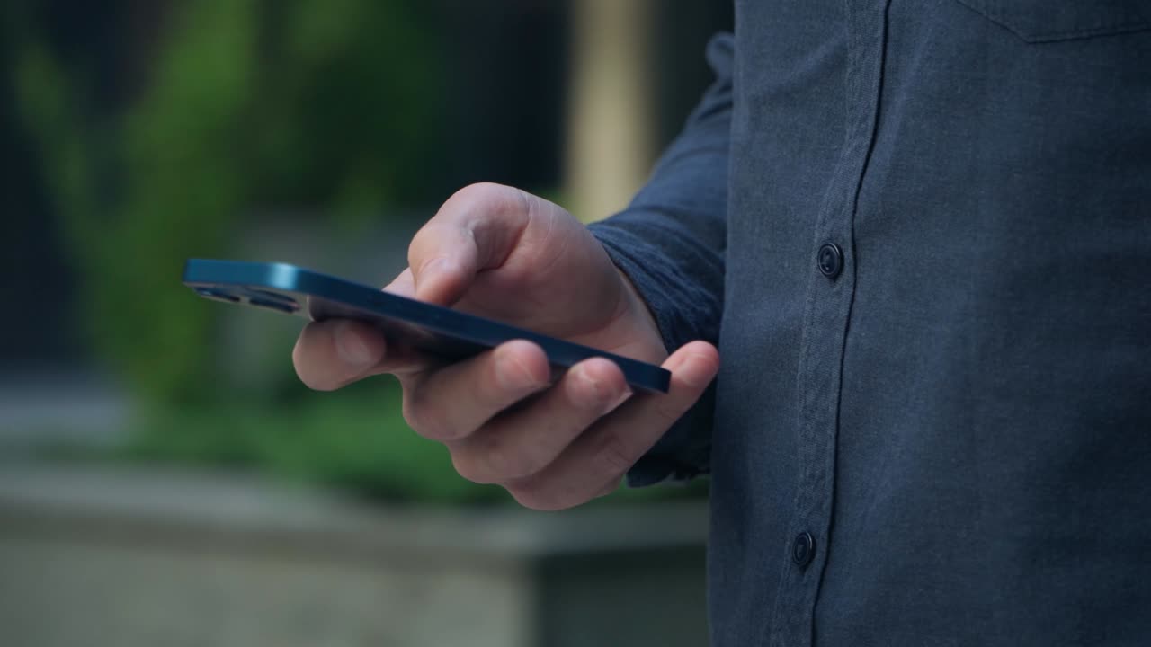 젊은이가 도시 중심의 거리에서 스마트폰을 사용합니다. 손에 스마트폰의 클로즈업.