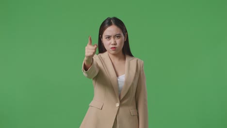 an angry asian business woman scolding while standing on green screen in the studio