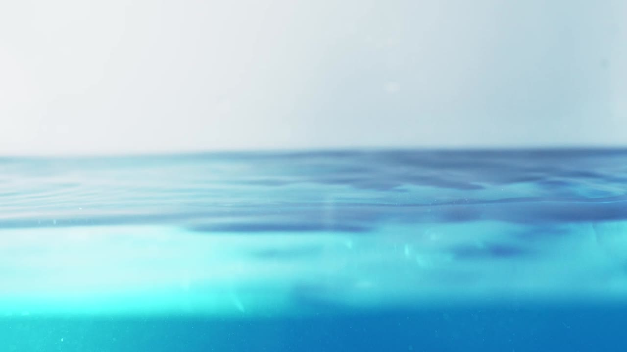 슬로우 모션의 깨끗한 물 표면은 물이 튀는 상점으로 화면을 채우고 기포로 액체 표면을 흔들고 있습니다.