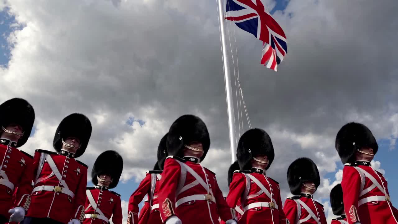 Vídeo a contrapicado de guardias británicos con uniformes rojos y sombreros de piel de oso, con un cielo espectacular