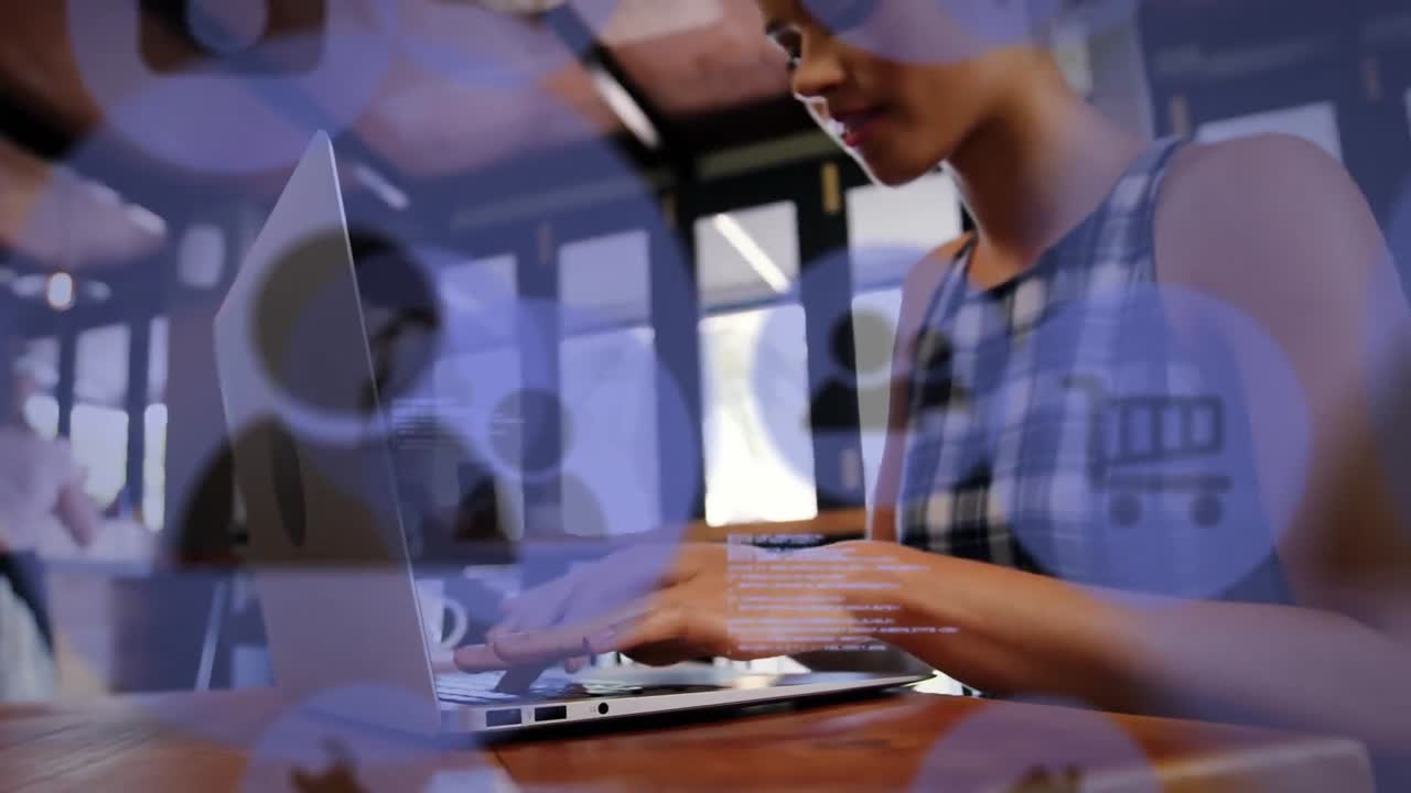 Animation of icons, computer language, low angle view of biracial woman working on laptop in cafes