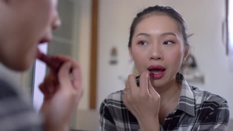 charming woman applying bright lipstick