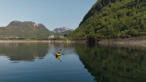 kayakers remando en el tranquilo lago roldalsvatnet en roldal, noruega, rodeado de exuberantes colinas verdes