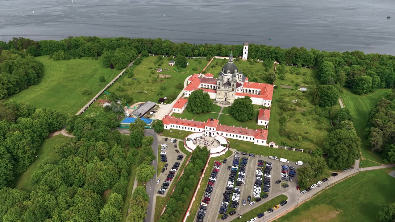 Splendide riprese aeree con drone del Monastero di Pazaislis a Kaunas, Lituania, circondato da una vegetazione lussureggiante, giardini curati e un lago scintillante sotto una luce diurna soffusa. Video drone nitido e cinematografico
