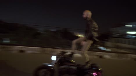 Un-Tipo-En-Motocicleta-Haciendo-Acrobacias-En-La-Ciudad-Parado-En-El-Asiento-En-La-Ciudad-Nocturna