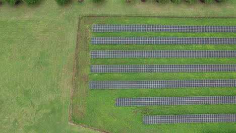 overhead shot of parallel lines set of solar panels built on green grass field