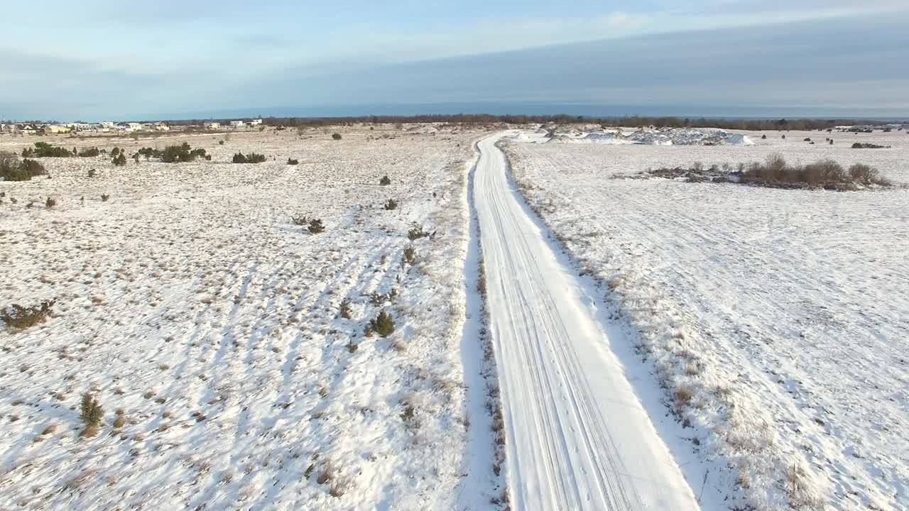 에스토니아 북부 숲에서 눈으로 인  빈 도로의 공중 사진.