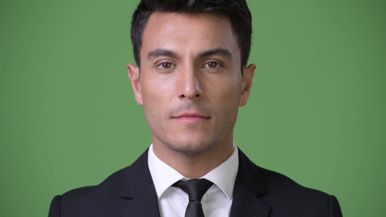 Jovem e bonito empresário hispânico contra fundo verde