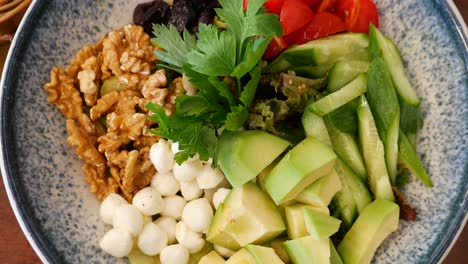 delicious and healthy salad with avocado, walnuts, mozzarella cheese, tomatoes and cucumber