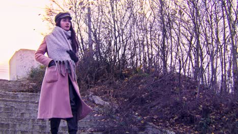 woman in pink coat and grey scarf on stairs in autumn