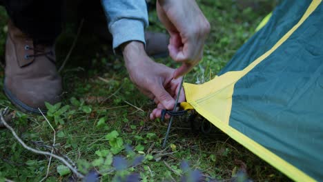 Nahaufnahme-Eines-Mannes,-Der-Ein-Zelt-Aufstellt,-Indem-Er-Beim-Zelten-Im-Wald-Einen-Hering-In-Den-Boden-Legt