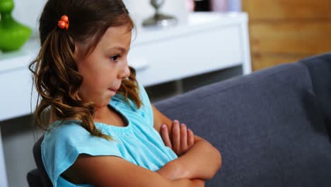 Sad-girl-sitting-with-arms-crossed-in-living-room