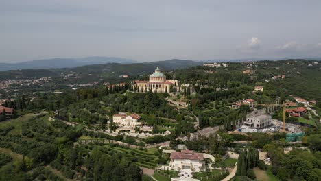 islamic looking architecture placed in centre of the city on a hill covered in nature with multiple modern buildings one of them being build crane next to it majestic looking location with mountains