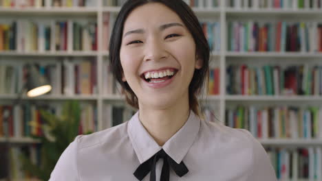 close-up-portrait-of-beautiful-cute-asian-woman-standing-in-library-laughing-and-smiling-bookcase-in-background