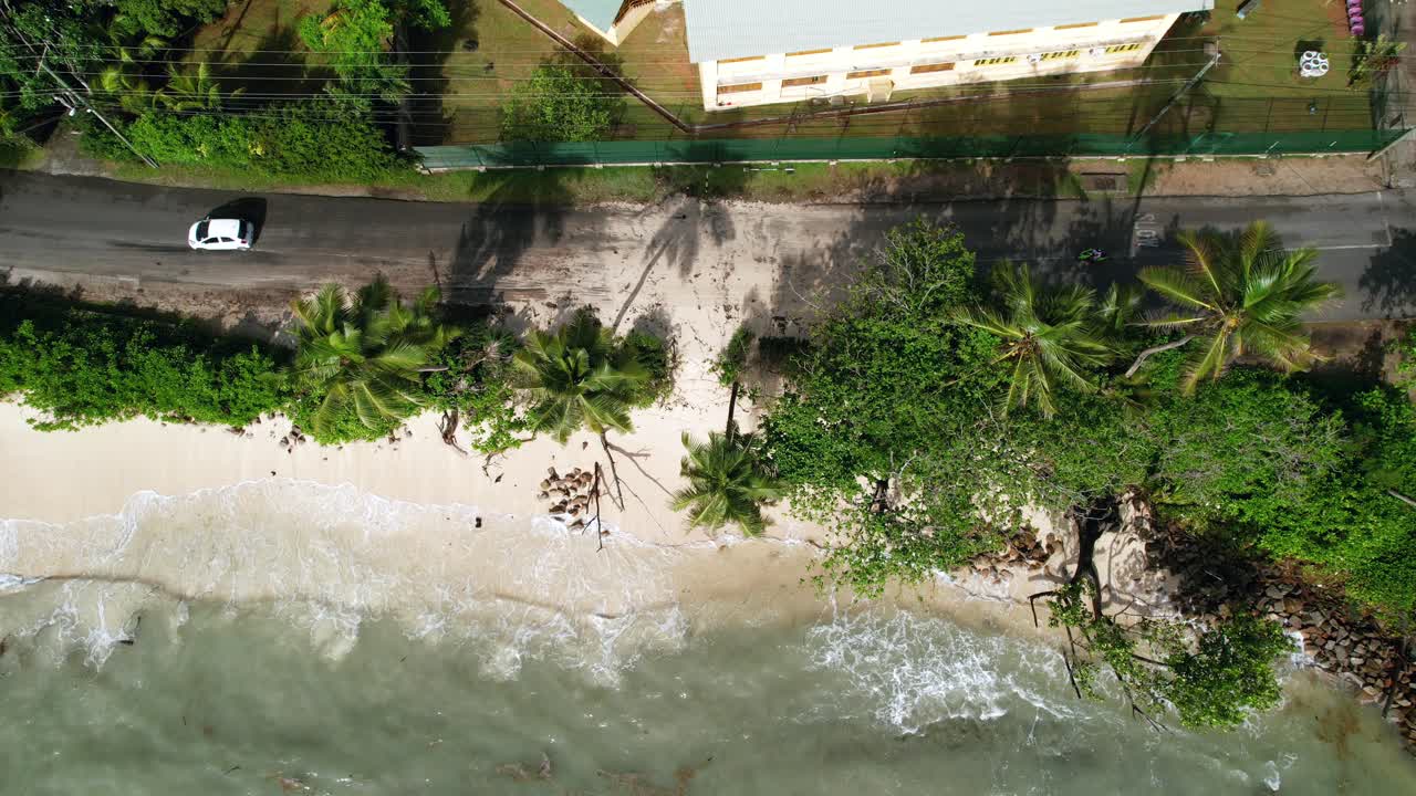 Drone shot of climate change, global warming, high tide that sea level rise until the main road, passing cars over sand, anse royale beach, Mahe, Seychelles 30fps