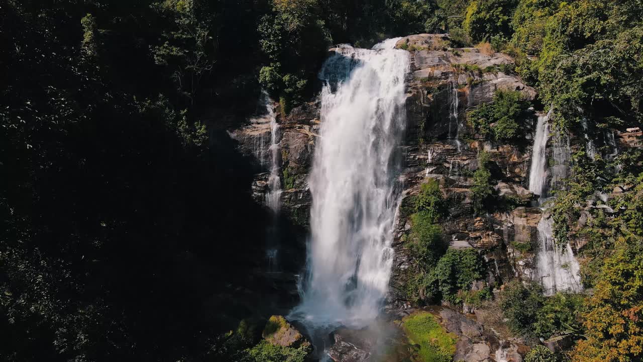agua espumosa blanca cae sobre la gran cascada rocosa de wachirathan entre la vegetación verde en un día soleado