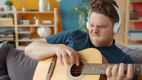 hombre tocando la guitarra acústica en casa