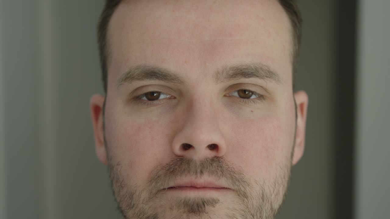 Primo piano di un uomo che arriccia ripetutamente il naso a causa di un tic nervoso. Concetto di movimento facciale involontario, stress, ansia e abitudine neurologica.