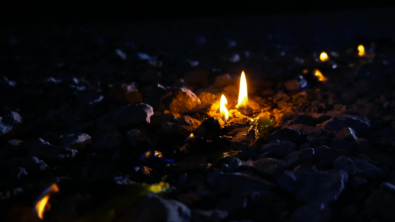 Rifiuti plastici gialli pericolosi che bruciano e si sciolgono a terra di notte, producendo fiamme arancioni brillanti e fumo tossico, causando un dannoso inquinamento ambientale da materiali pericolosi