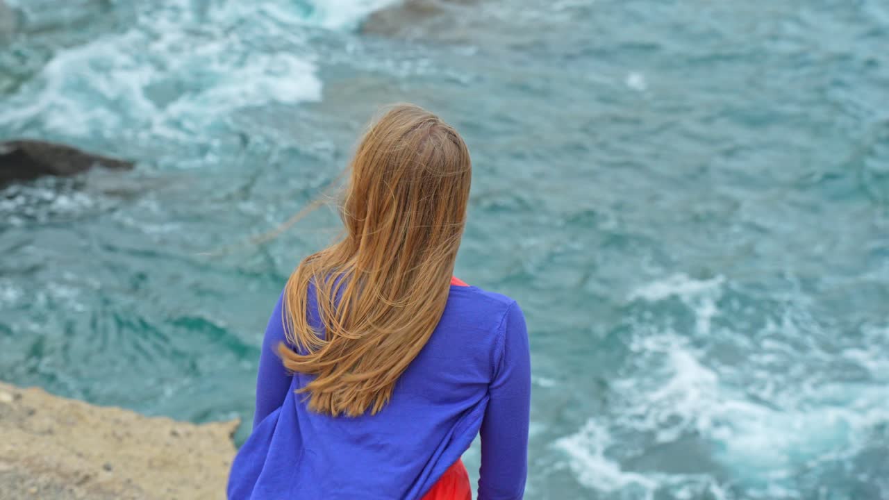 Closeup shot of woman's back looking at waves on a windy day, Tenerife
