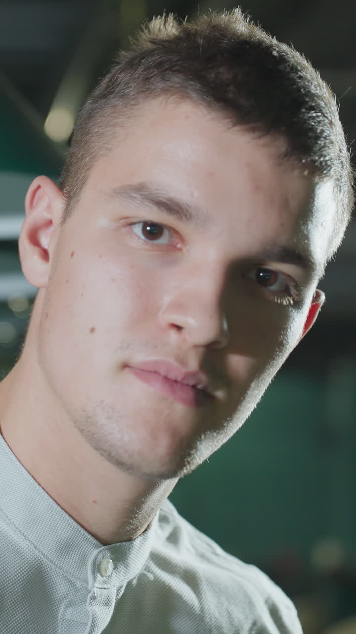 Primo piano di un uomo in camicia bianca che tiene in mano una stecca da biliardo in una sala da biliardo scarsamente illuminata. Le luci dall'alto proiettano ombre delicate sul suo viso concentrato. Il tavolo da biliardo verde e le luci sospese creano una profondità suggestiva