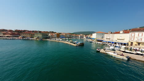 low flying aerial fpv drone along water establishes dock of cres island croatia