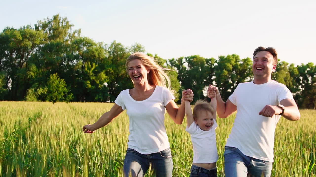 familia feliz, madre padre e hijo en un paseo emocional. corriendo y disfrutando de la vida en un campo verde en el aire fresco, cielo azul, naturaleza