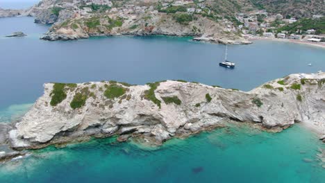 aerial past rocky outcrop of bay with turquoise waters in crete