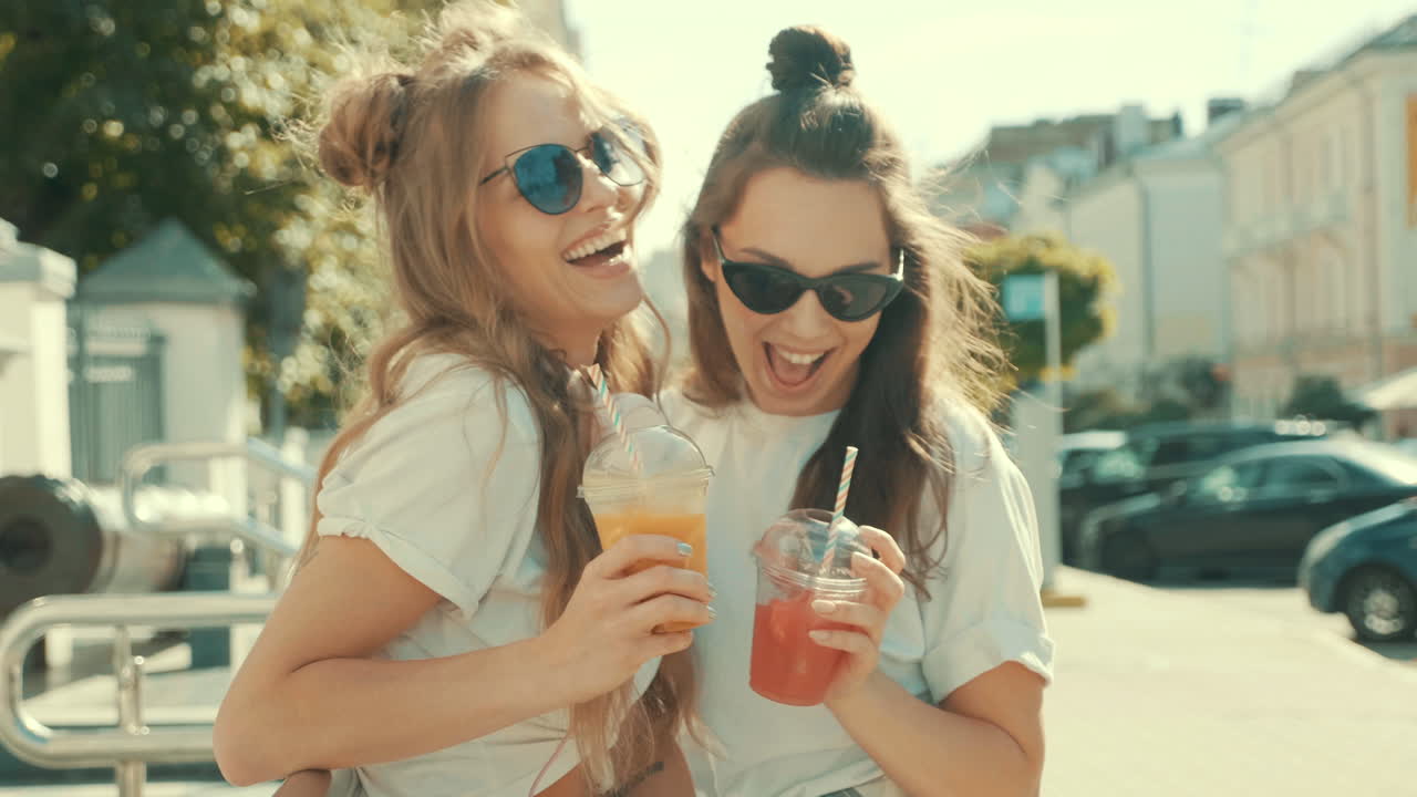 dos amigos felices disfrutando de bebidas en una calle de la ciudad