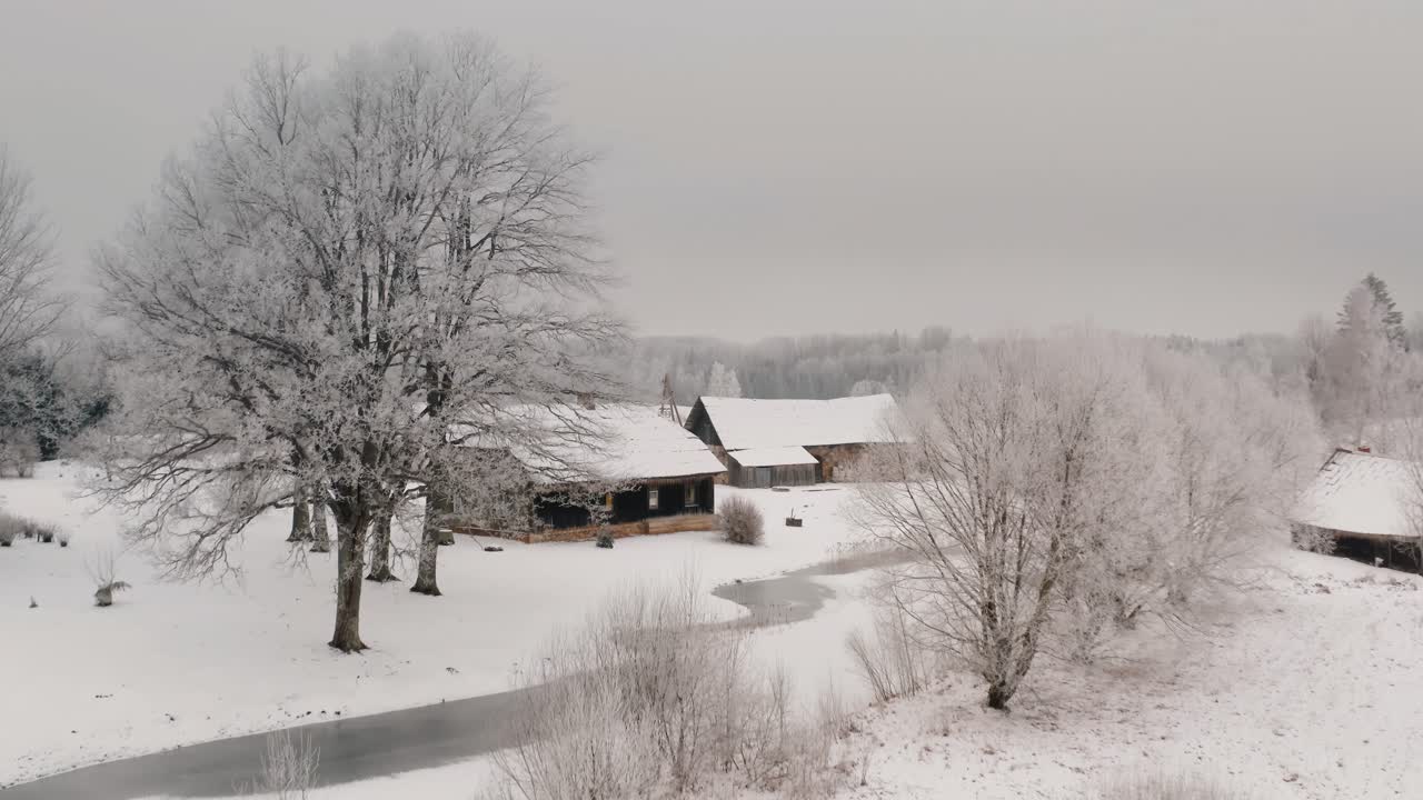 Historic wooden family house in the suburbs. Winter season with snow on the ground and frozen trees. Aerial view of historic community in the countryside. Winter wonderland scenery.