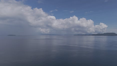 Sea-view-with-horizon-and-calm-sea-with-storm-clouds-reflecting-off-ocean-and-blue-skies