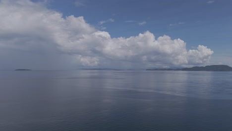 sea view with horizon and calm sea with storm clouds reflecting off ocean and blue skies