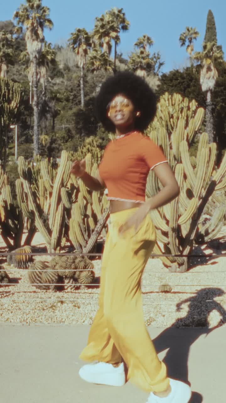 Giovane donna nera con afro che balla con gioia in un giardino desertico