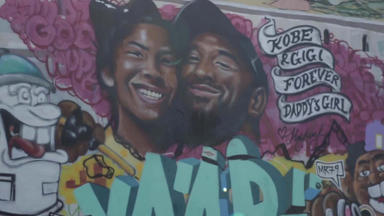 Close Up of Kobe and Gigi Bryant Mural, Slow Motion, Dust and Light in Foreground