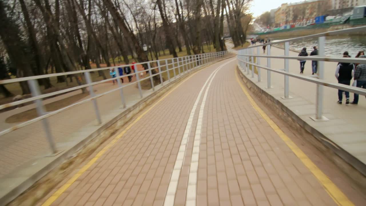 Cycling on bicycle path along embankment in city park. Speed cycling