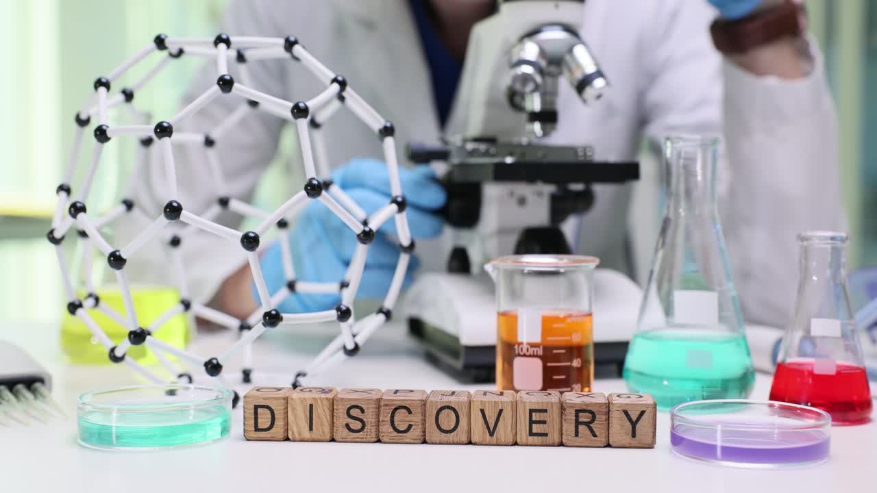 A laboratory scene with scientific equipment and a person, featuring the word "DISCOVERY" in the foreground