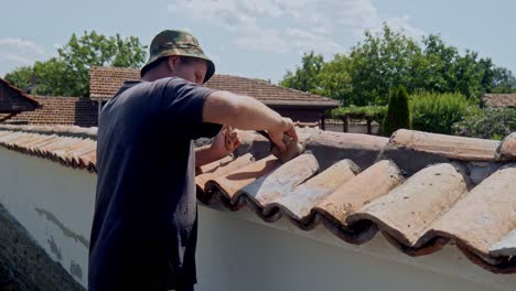 Man-on-work-platform-brush-cleans-terracotta-tiled-wall-of-cement-dust