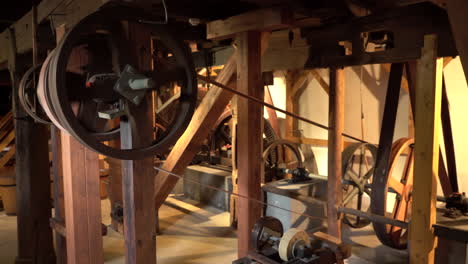 handheld wide shot inside old heritage mill - spinning wheels with transmission