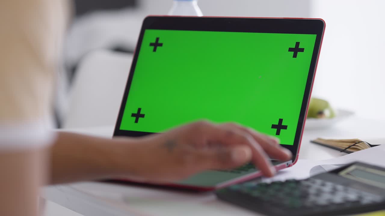 portátil de primer plano con pantalla verde y hombre afroamericano con mano tatuada escribiendo en el teclado. tipo irreconocible navegando por internet mensajería en línea en la oficina de casa. dispositivo chromakey.