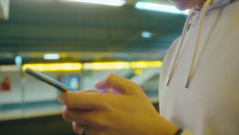 girl texting on the phone on underground platform