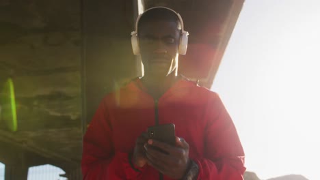 African-american-man-checking-smartphone-taking-break-during-exercise-outdoors-by-the-sea