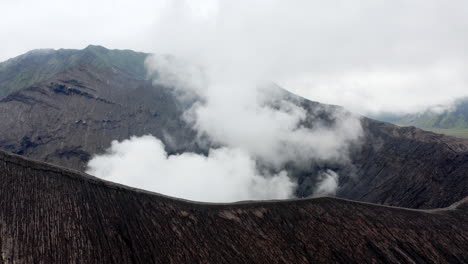 erupting mt bromo, extreme aerial long shot with man on hiking track