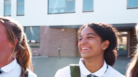 portrait of smiling female high school students wearing uniform outside college building