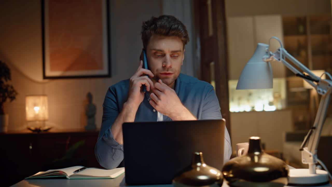 Primo piano di uno studente serio che parla al telefono a casa di sera. Uomo che parla al cellulare.