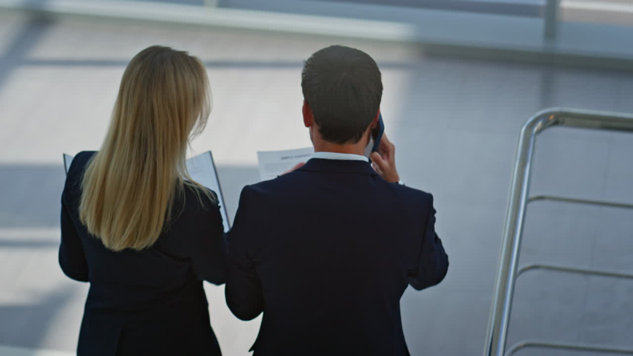 Manager aziendali che discutono di documenti salendo le scale, vista dall'alto verso il basso