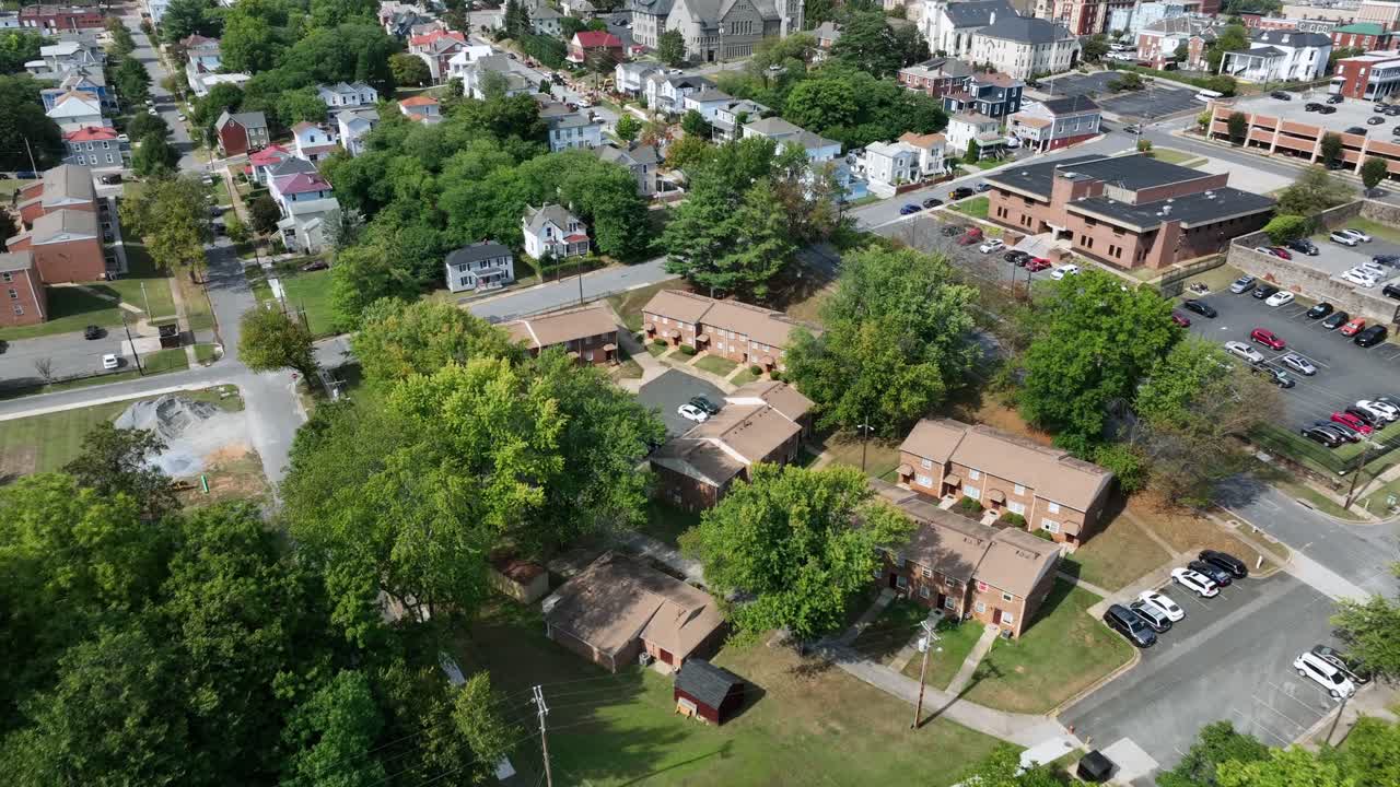 Slow drone flight over apartment blocks in residential area of America. Town. Sunny summer day in downtown of Lynchburg, Virginia. Green trees, parking Cars and office buildings